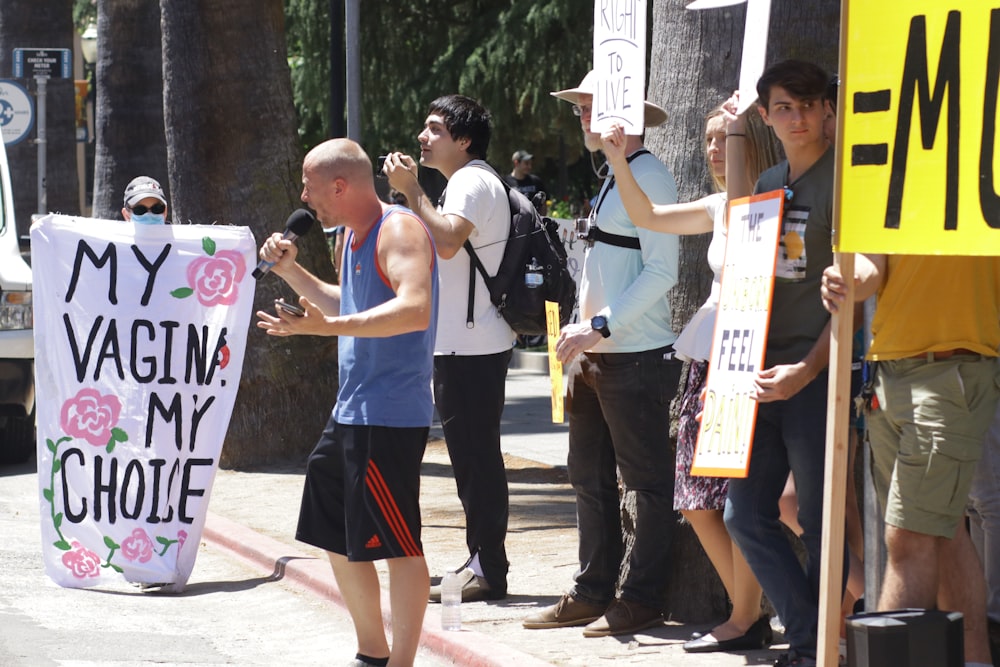 a group of people holding signs on the side of the road