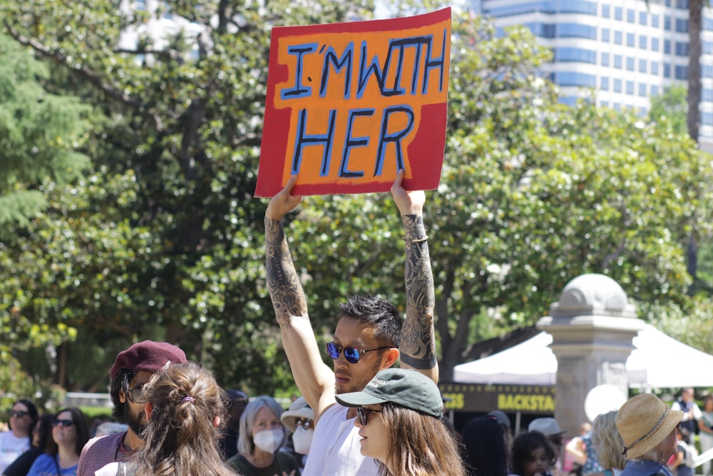 a man holding a sign that says i'm with her