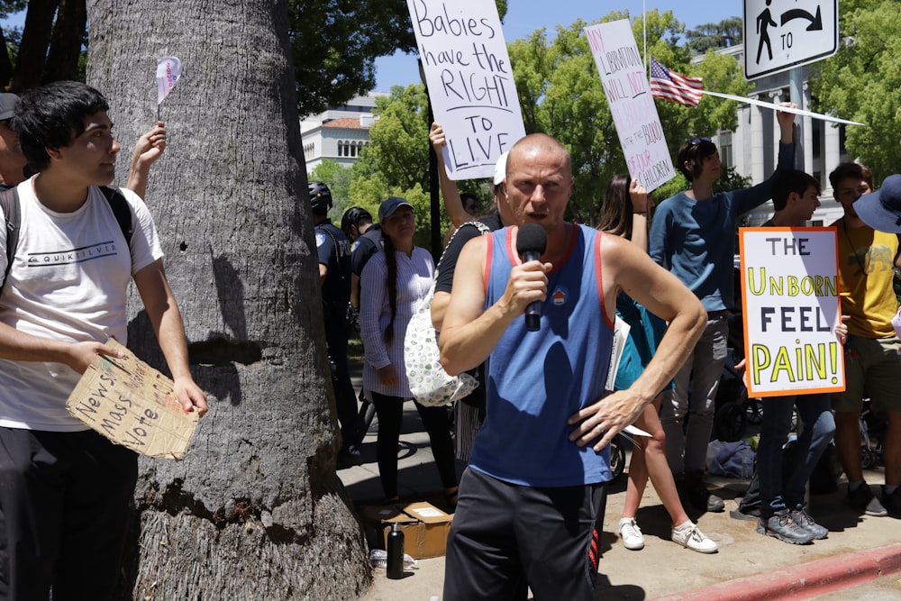 a man standing next to a tree holding a microphone