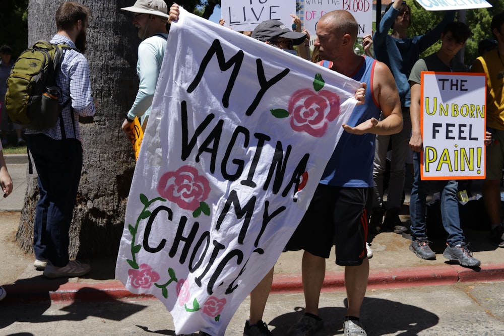 a man holding a sign that says my vagina is my choice