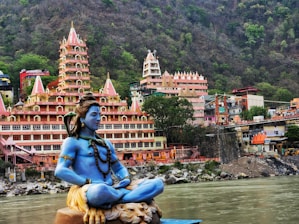 a statue of a person sitting on a rock in front of a body of water
