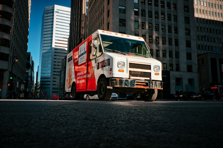 A red and white truck driving down a street
