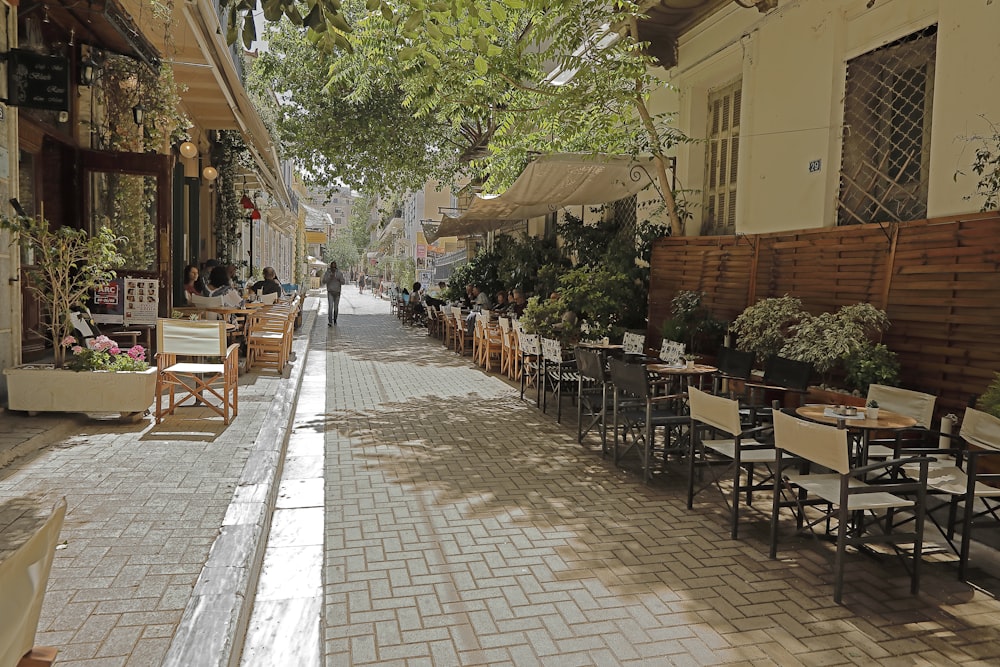 a street lined with tables and chairs next to trees