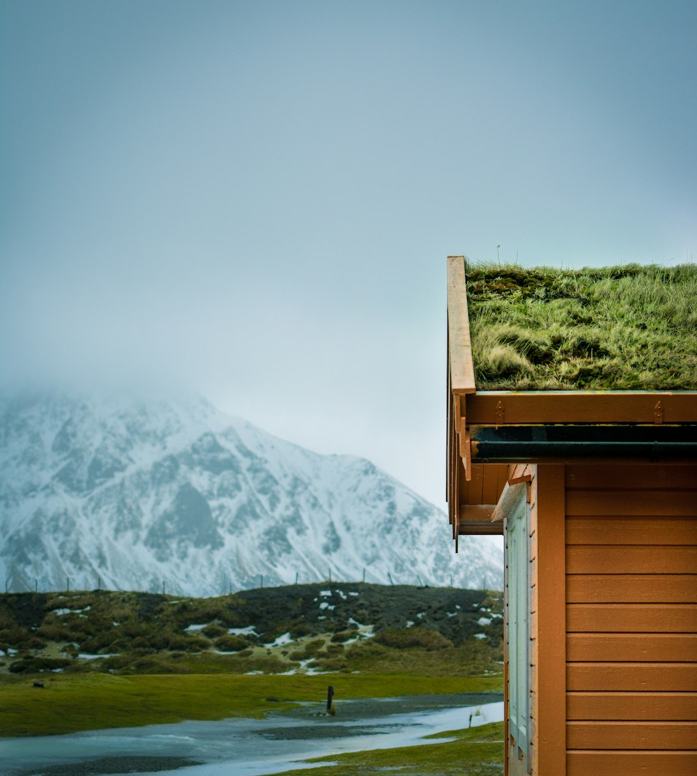 a house with a green roof and a mountain in the background