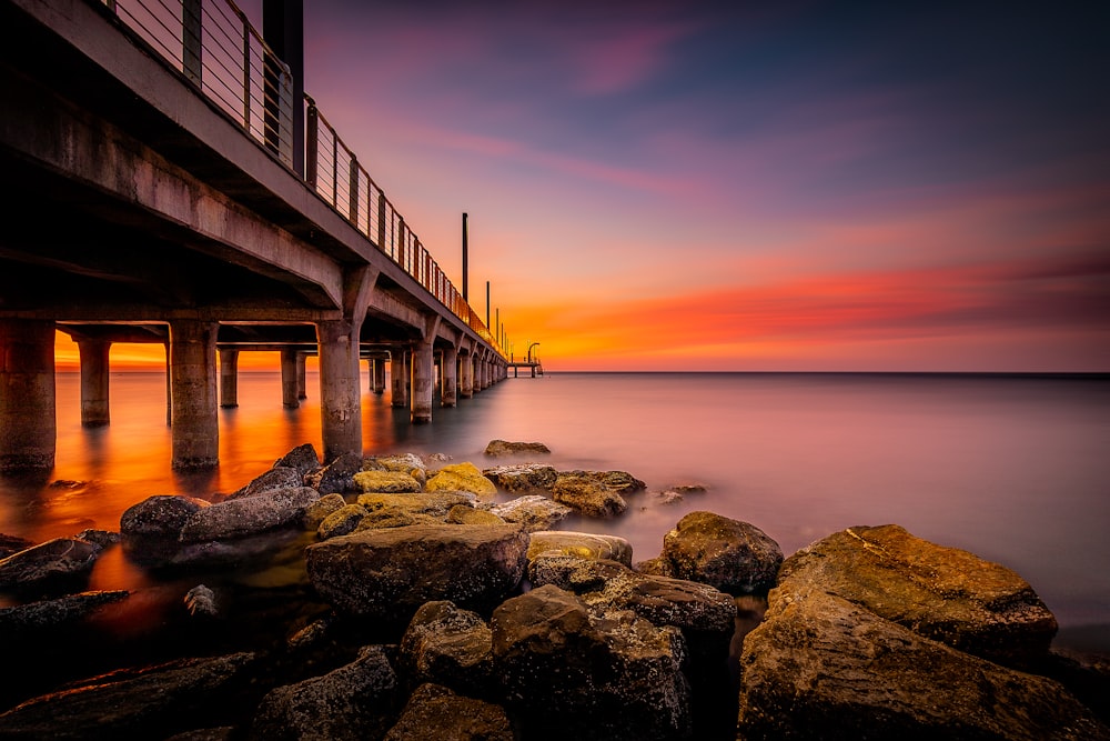 a long bridge over a body of water at sunset