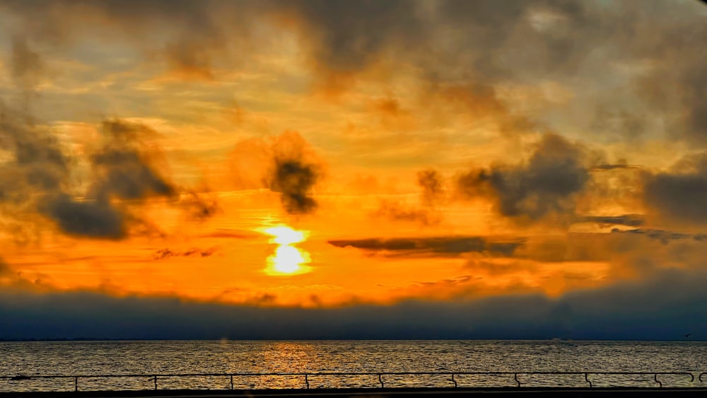 the sun is setting over the ocean on a cloudy day