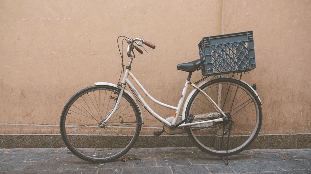 a white bicycle parked next to a tan wall