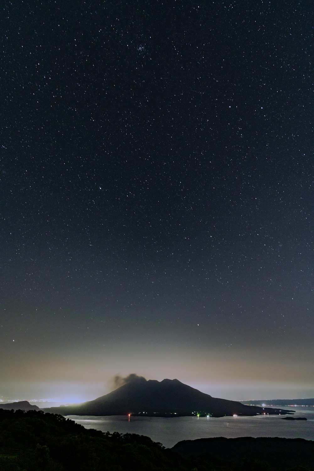 the night sky with stars and a mountain in the distance