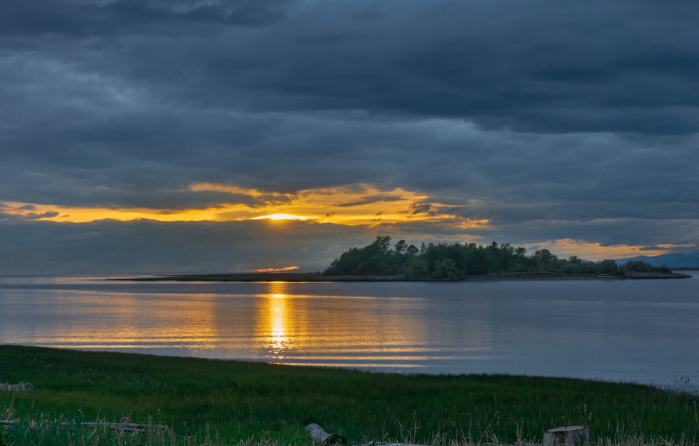 a sunset over a body of water with a small island in the distance