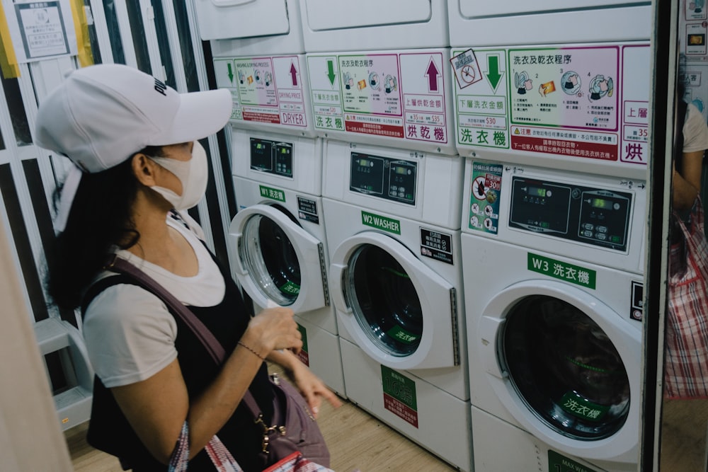 a woman wearing a face mask in front of a row of washers