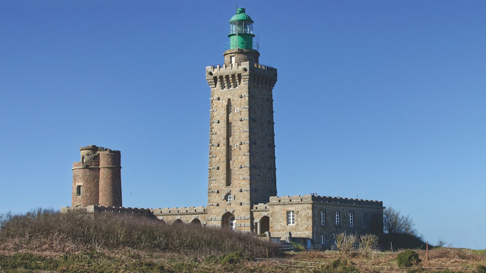 a tall tower with a green top on top of a hill