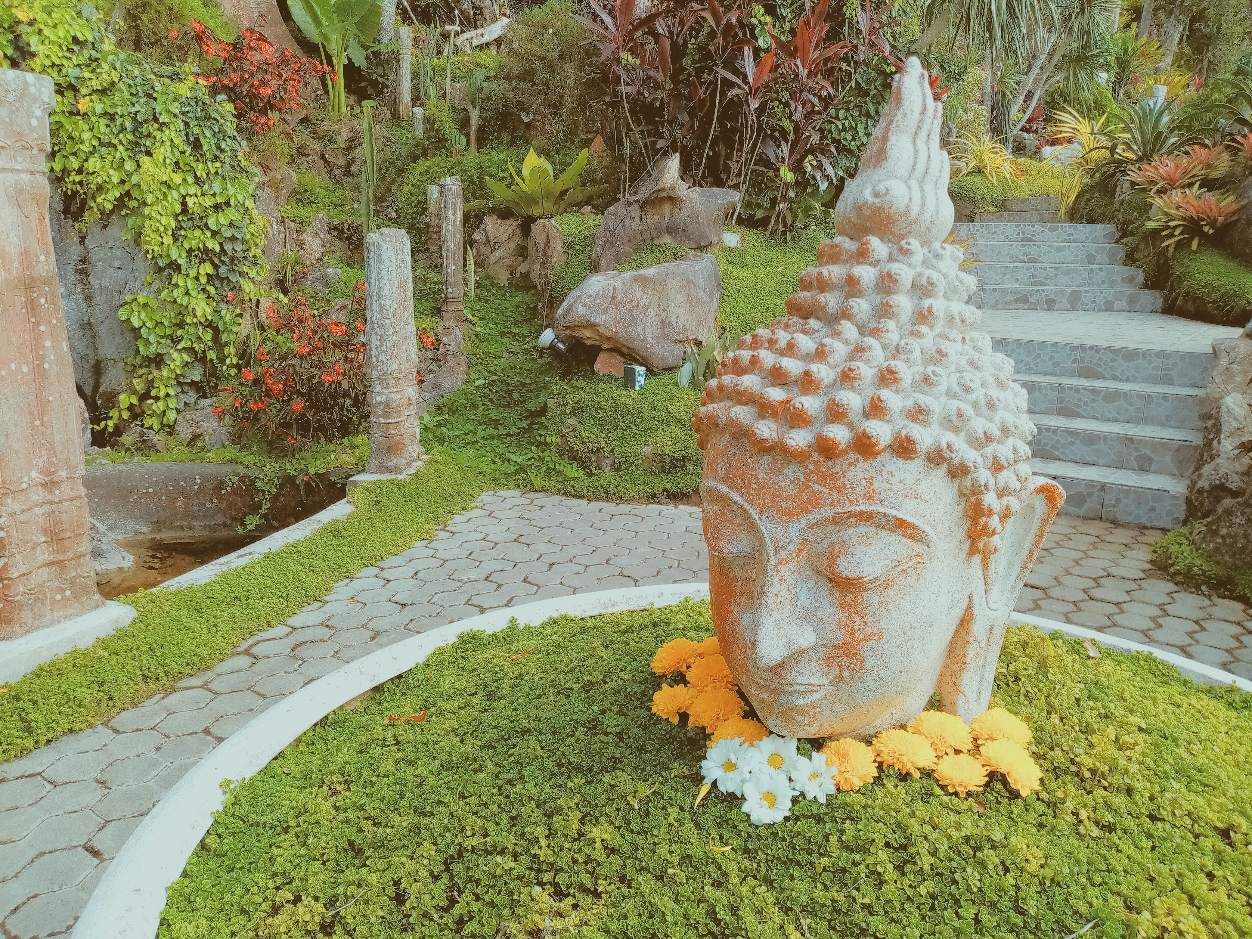 a statue of a buddha sitting on top of a lush green field