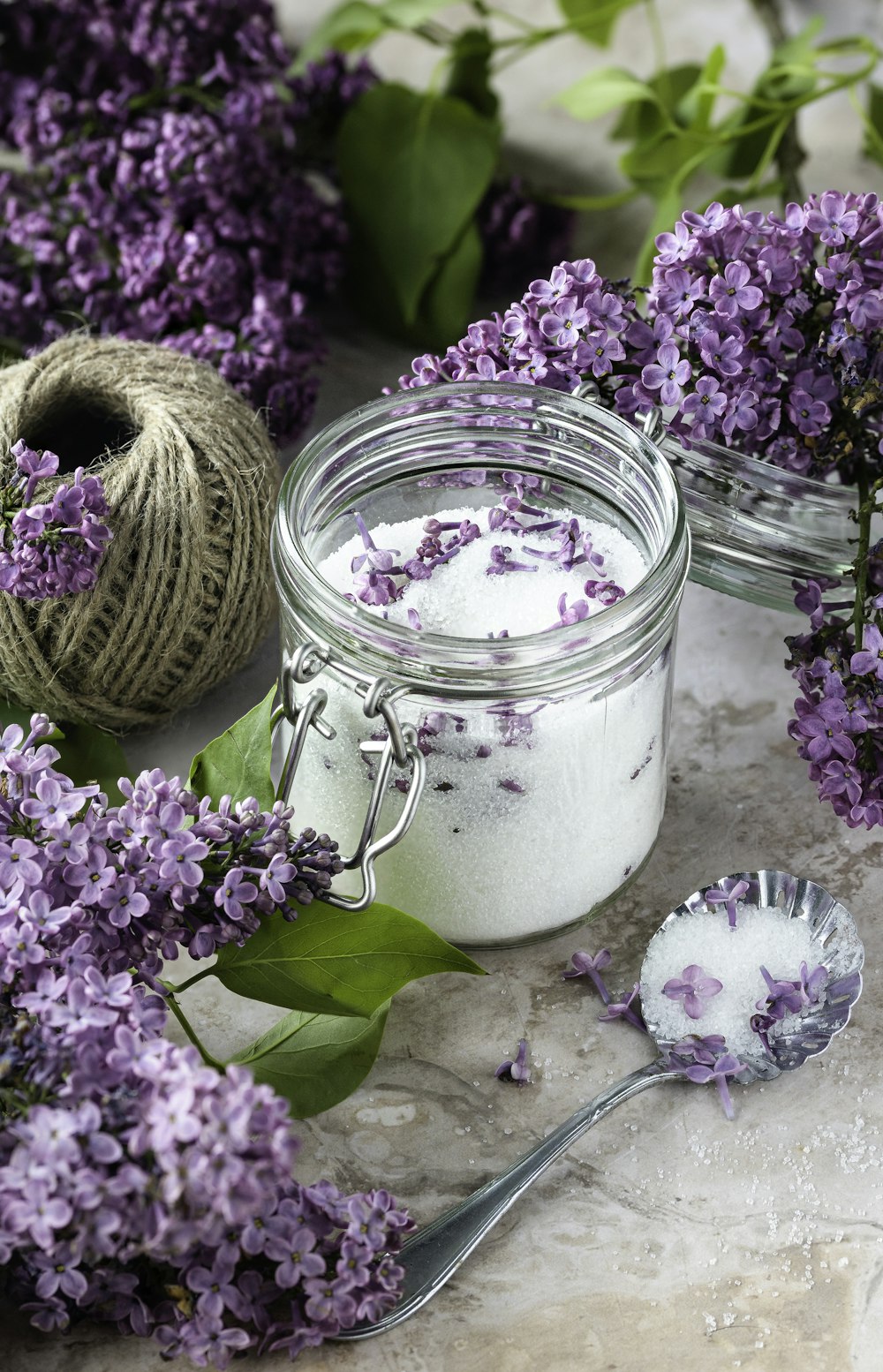 um frasco cheio de flores de lavanda ao lado de uma bola de barbante