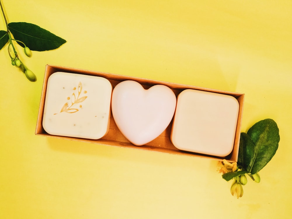 three soaps in a wooden box on a yellow background