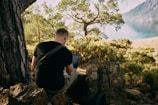 a man sitting on top of a rock next to a tree