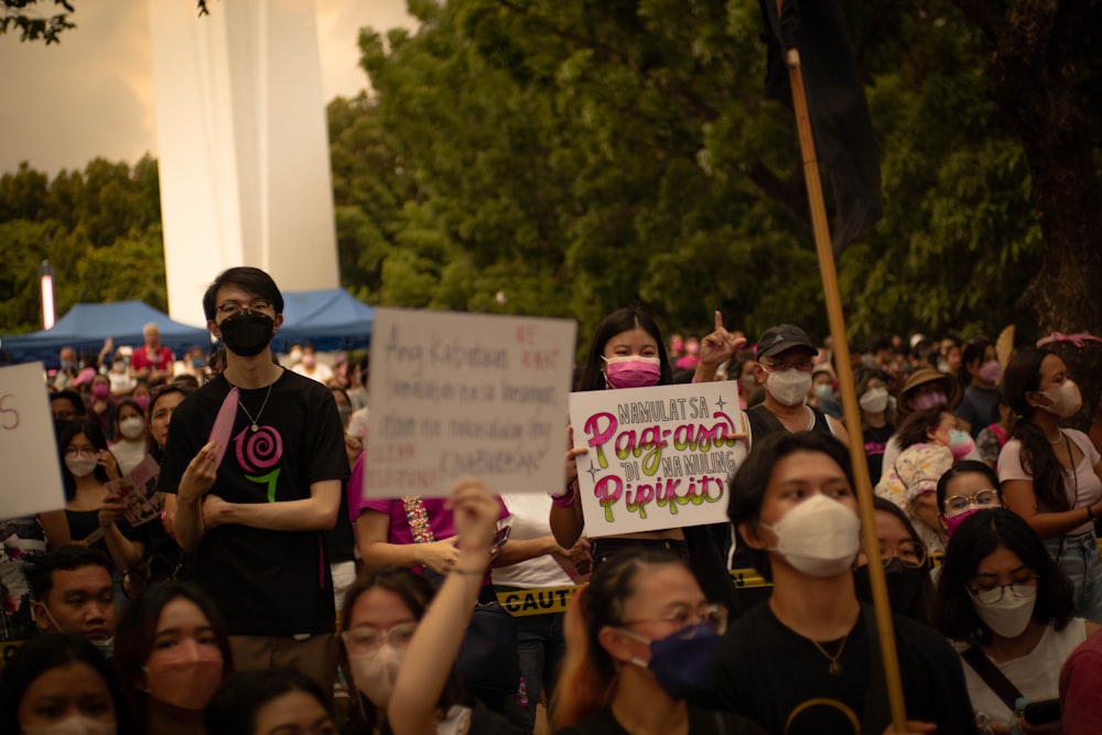 a group of people holding signs and wearing masks