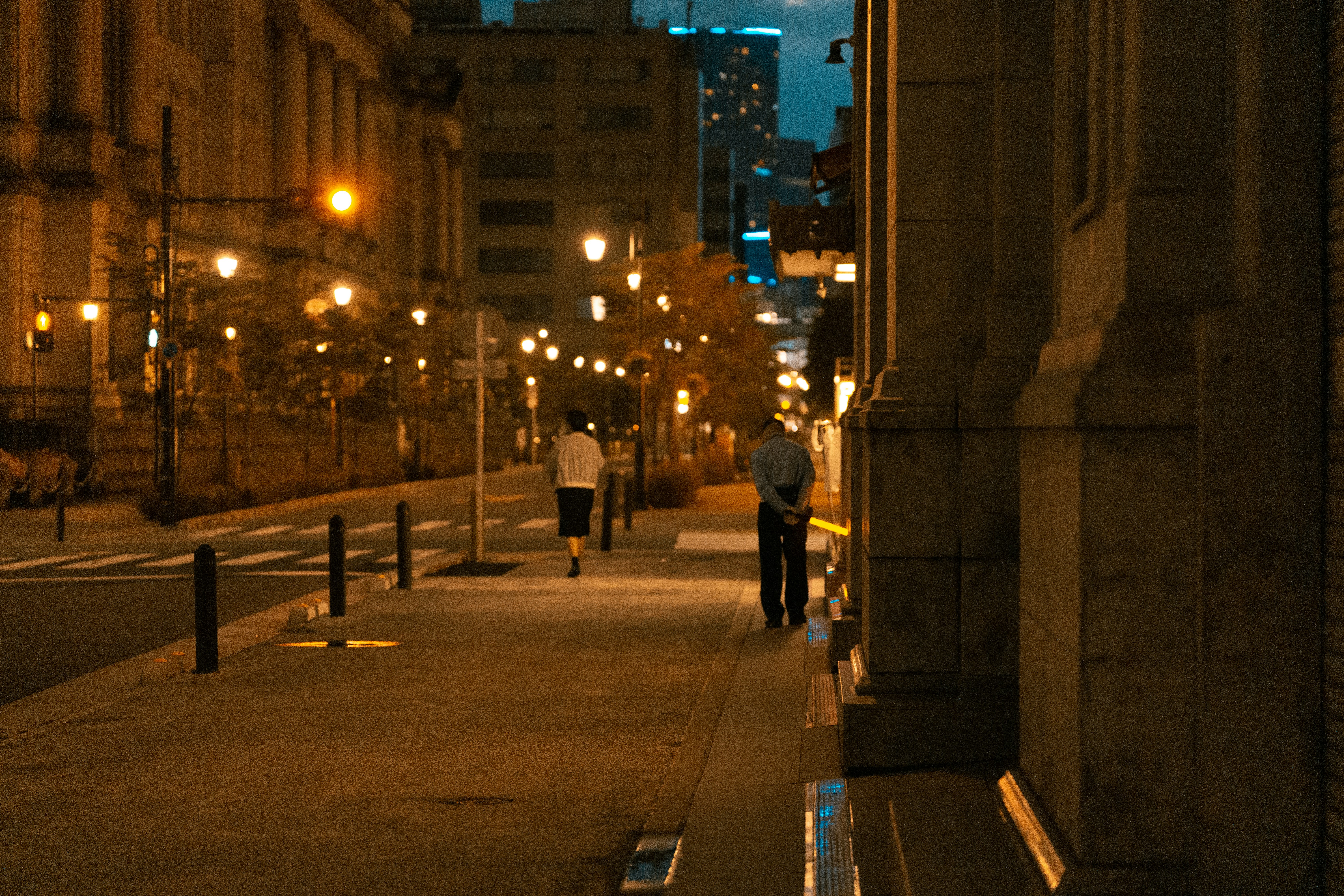 a couple of people walking down a street at night