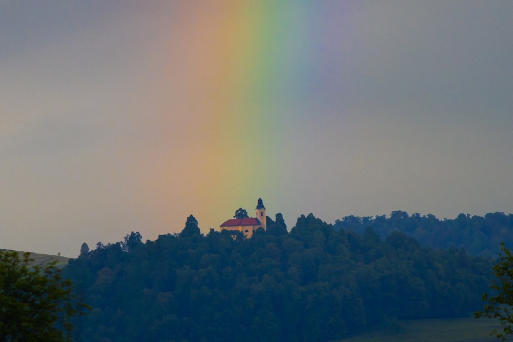 a rainbow appears over a church on a hill