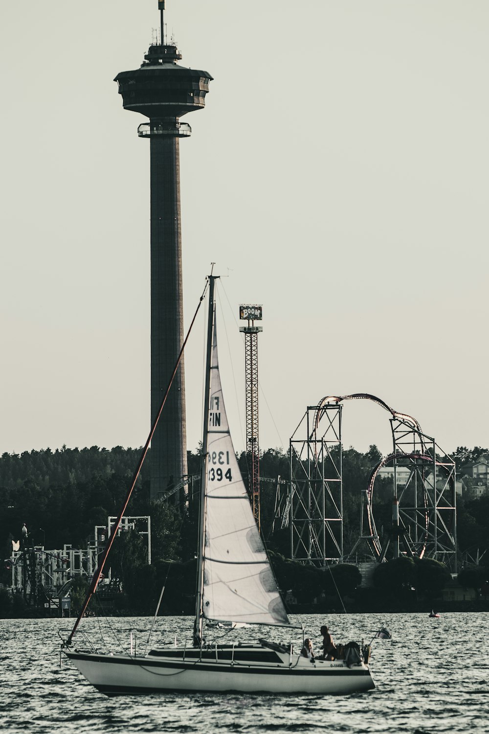 a sailboat in a body of water with a tower in the background