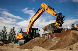 a yellow and black excavator on a pile of dirt