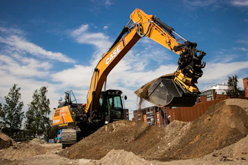 a yellow and black excavator on a pile of dirt