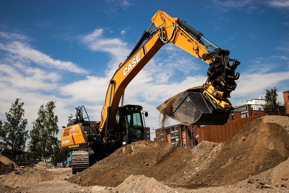 a yellow and black excavator on a pile of dirt