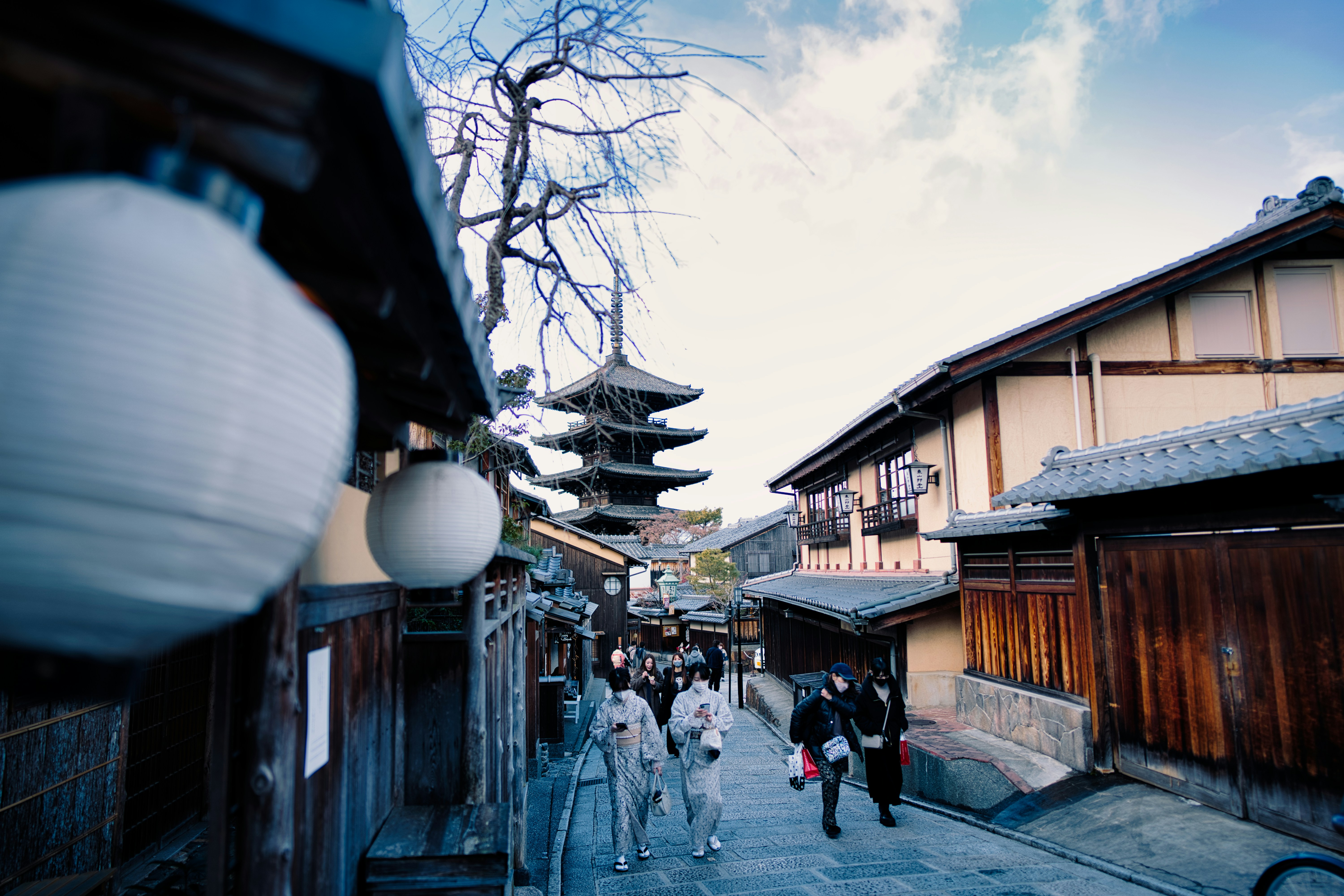 a group of people walking down a street next to tall buildings, 
