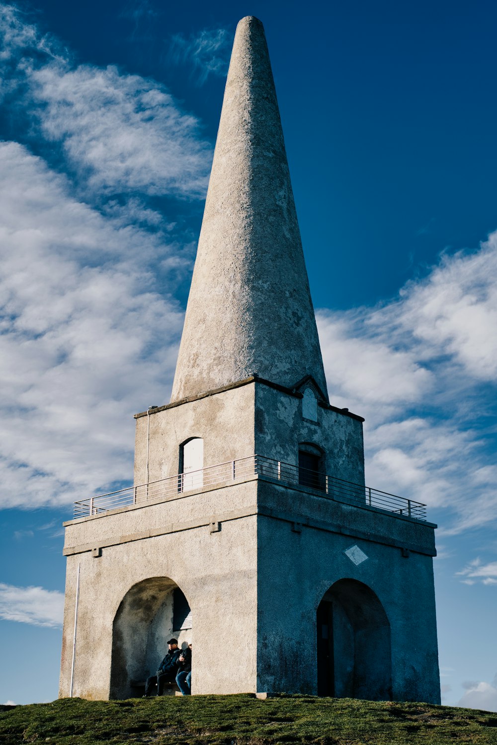 a tall tower with a man sitting on top of it