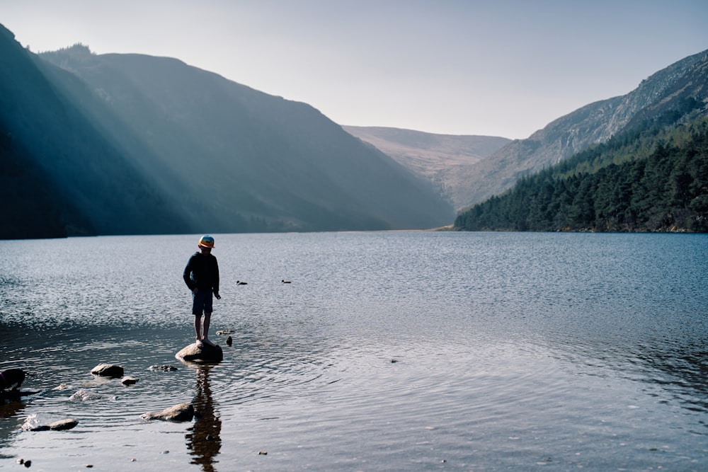 a man standing on a rock in the middle of a lake