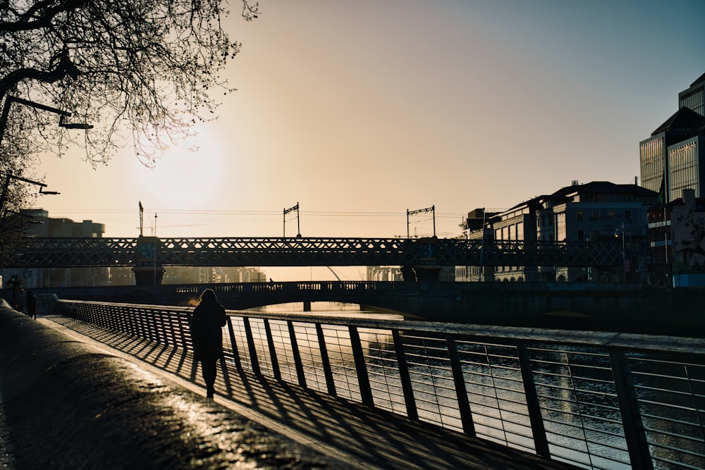 a person standing on a bridge next to a body of water