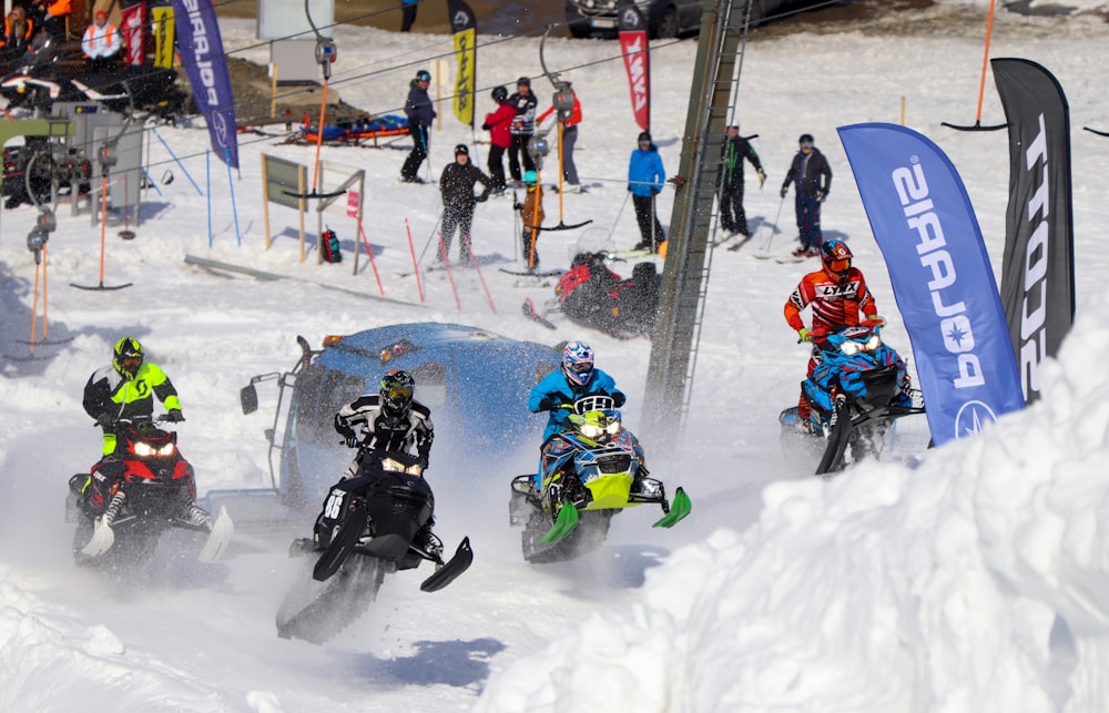 a group of people riding snow bikes down a snow covered slope