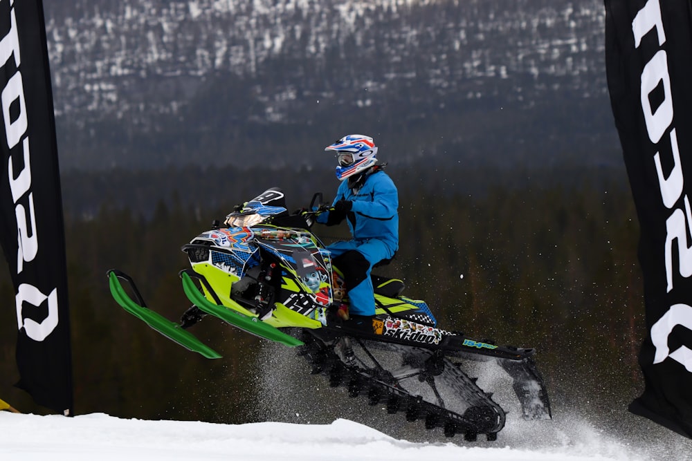 a man riding a snowmobile on top of a snow covered slope