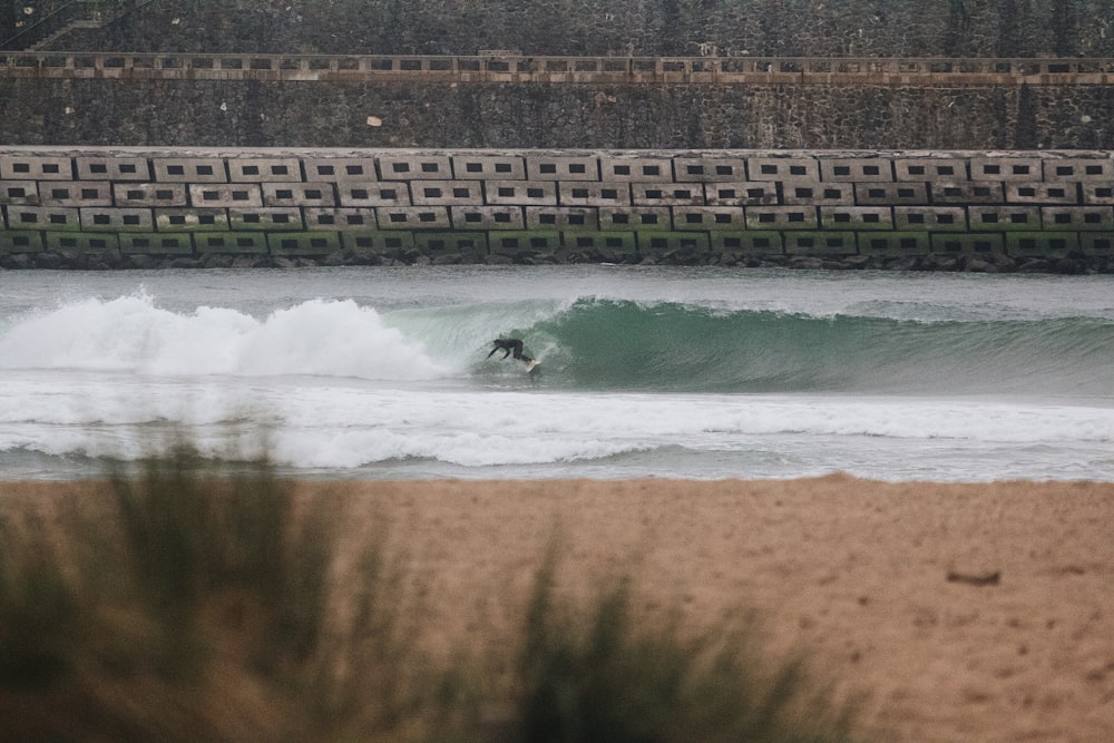 una persona montando una ola encima de una tabla de surf