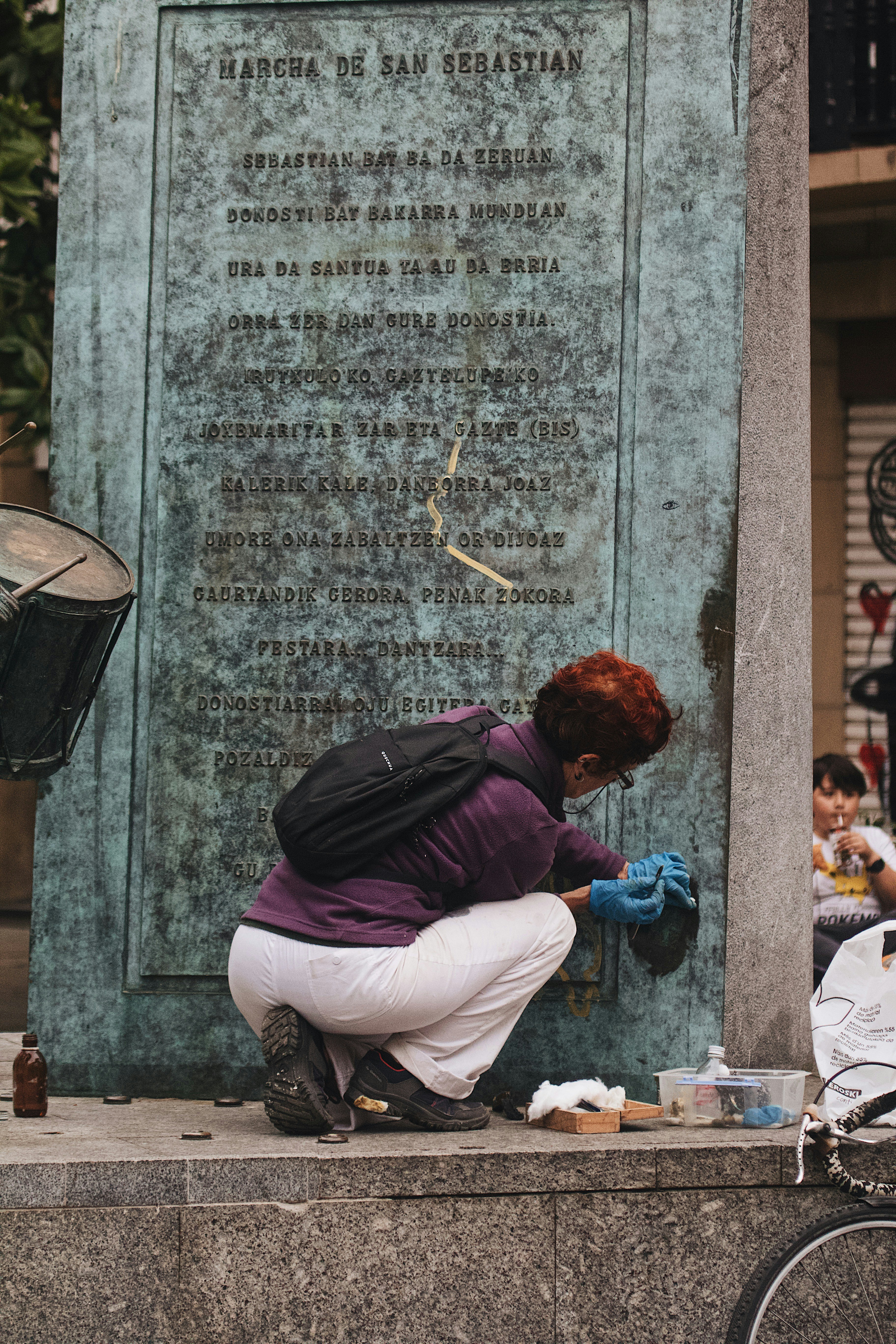 A woman kneeling down next to a monument - marker adoption service learning