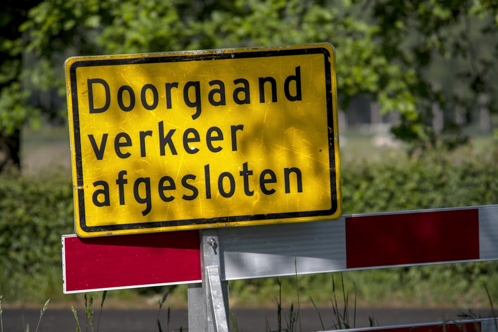 a yellow and red sign sitting on the side of a road