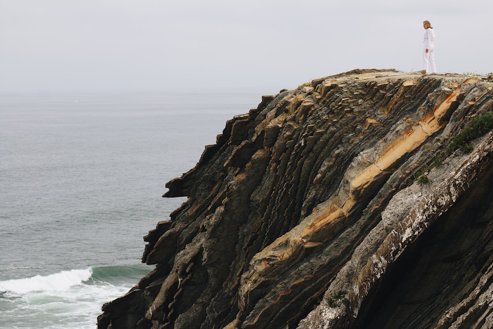 a person standing on top of a cliff near the ocean