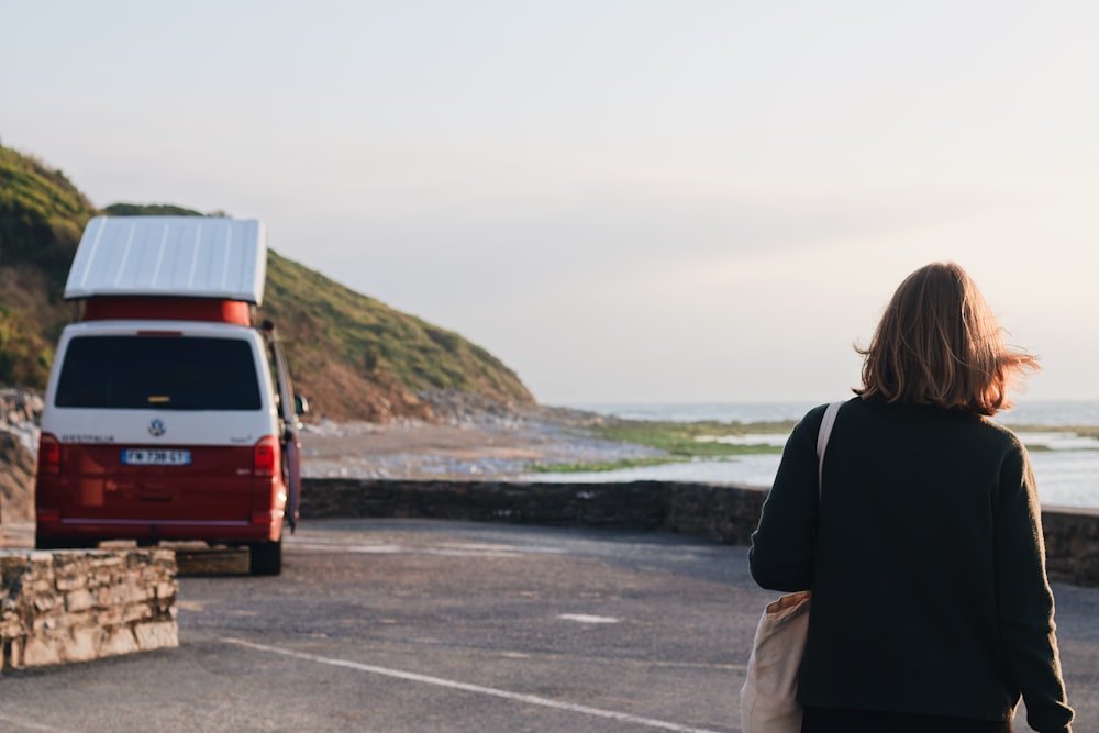 a woman standing in a parking lot next to a van