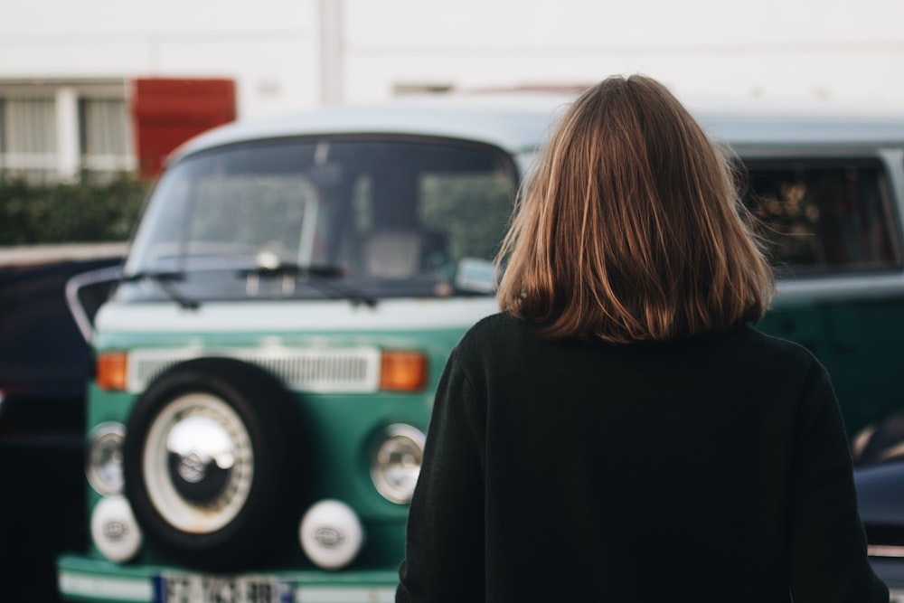 a woman standing in front of a green and white bus