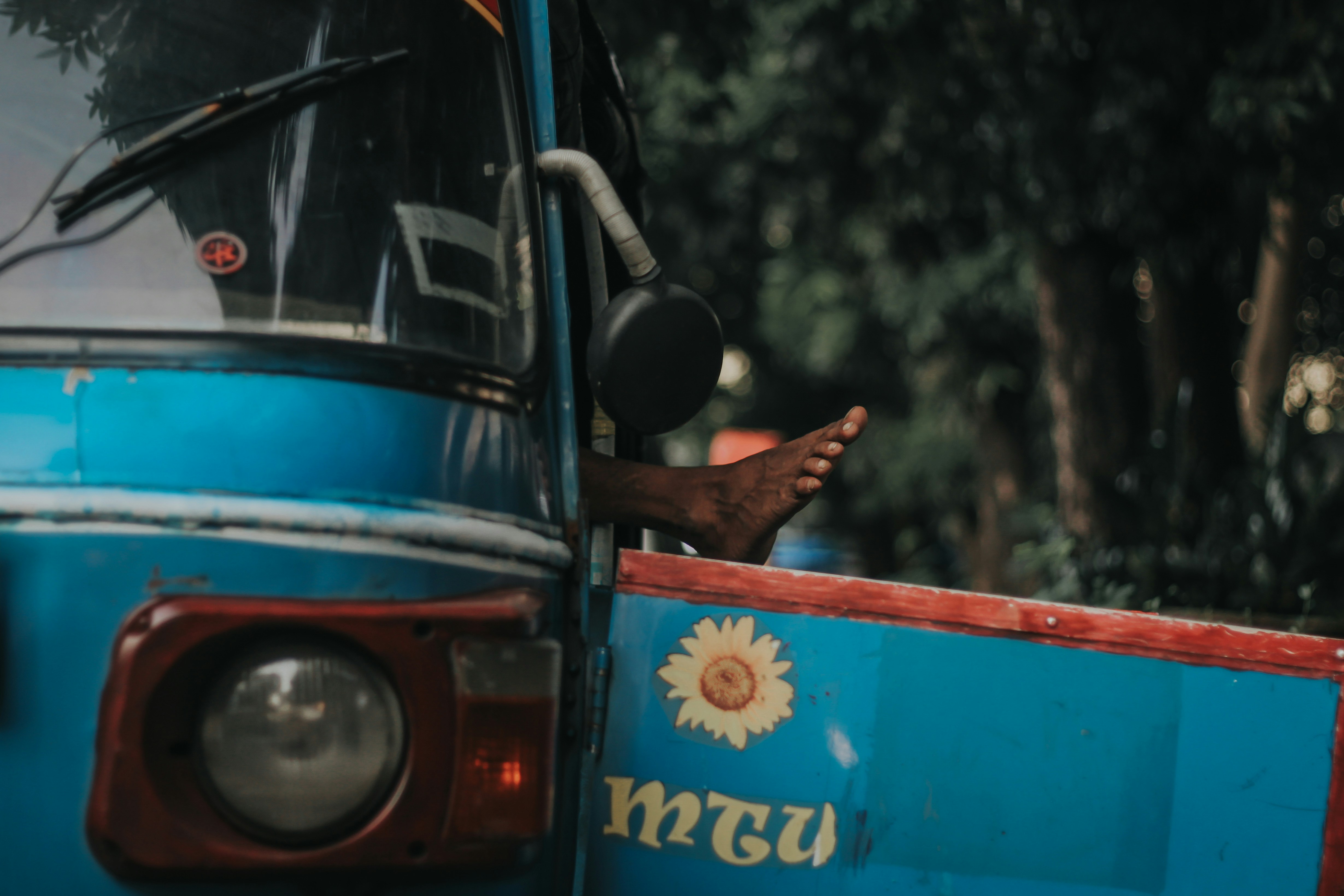 a blue bus with a person's foot sticking out of the window
