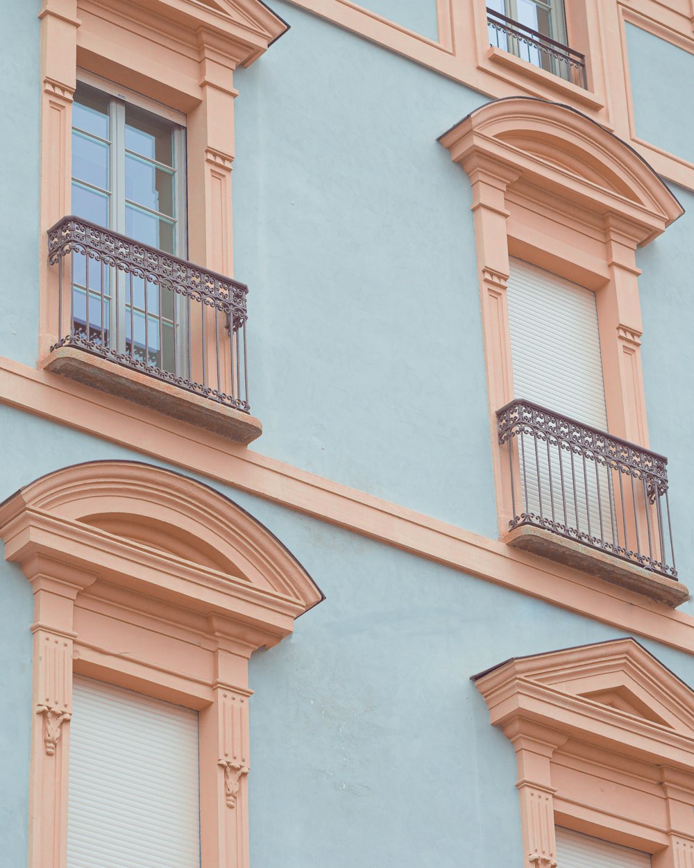 a blue building with two balconies and a clock