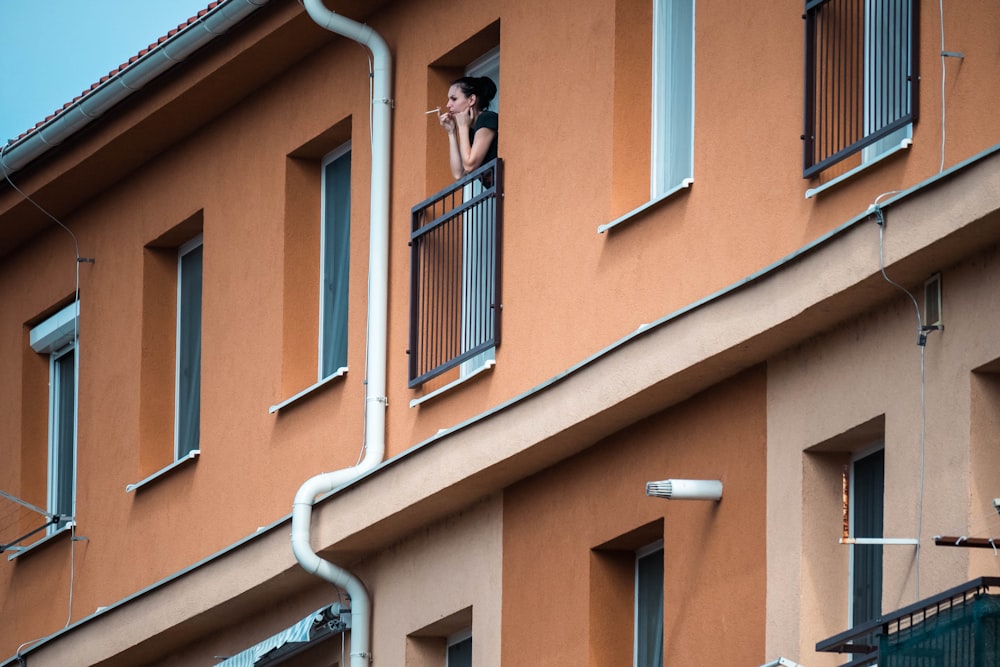 a woman standing on a balcony looking out of a window