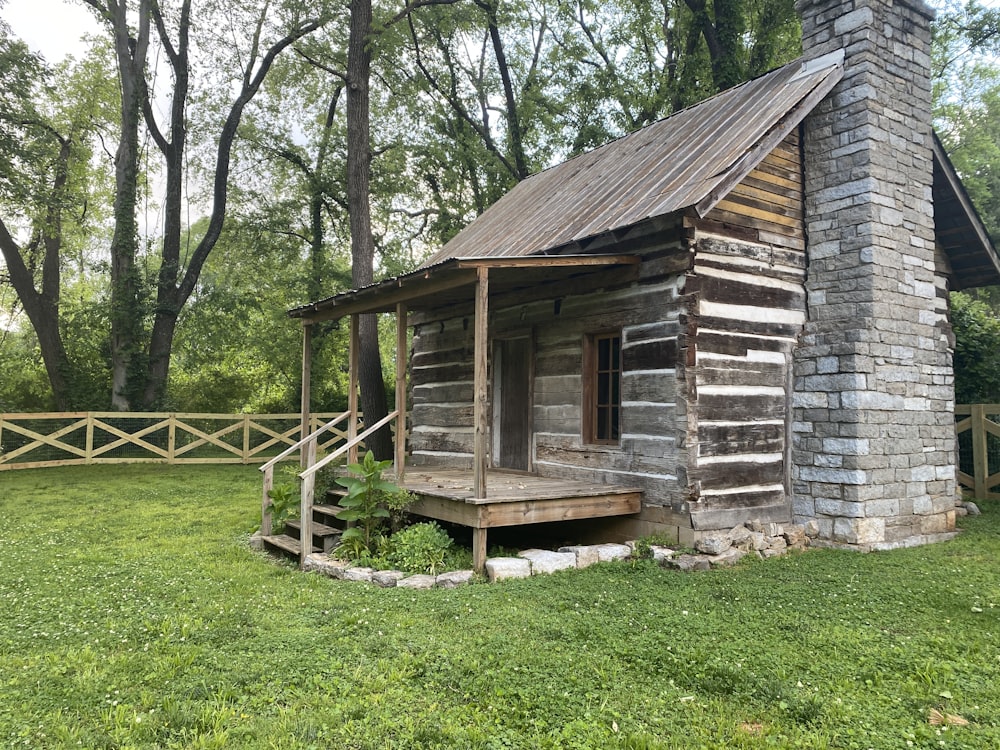 an old log cabin sits in a grassy field