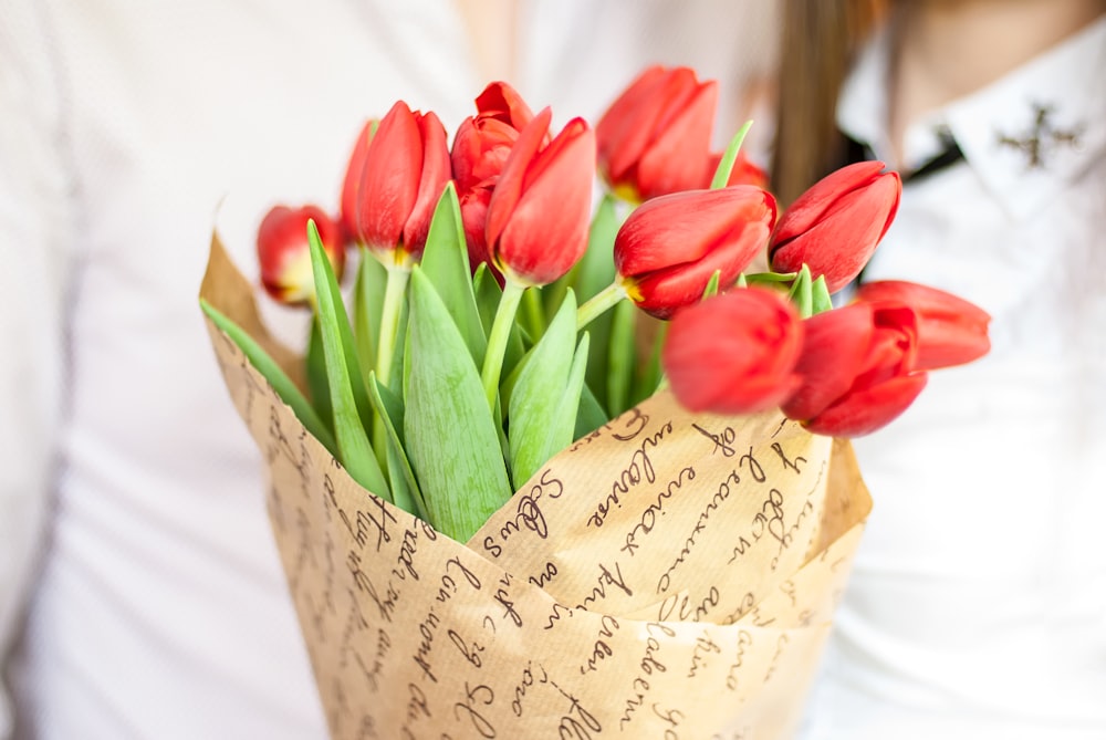 a bouquet of red tulips in a paper bag