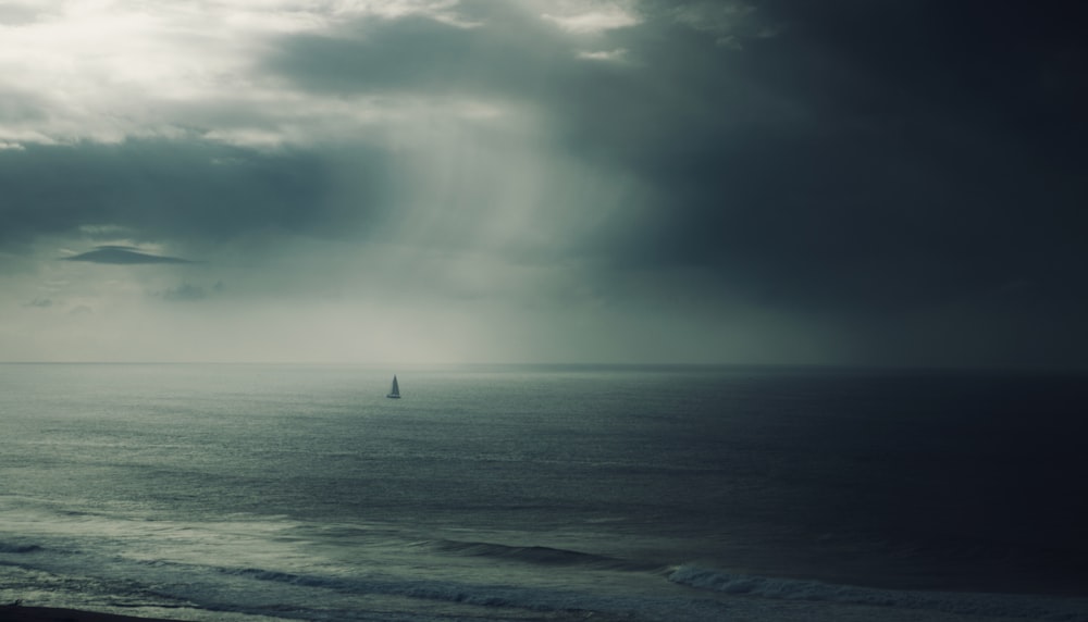 a sailboat in the ocean under a cloudy sky