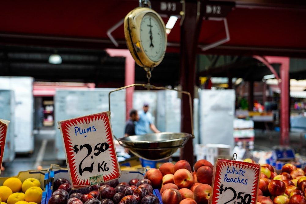 un banco di frutta con mele, prugne, arance e altra frutta