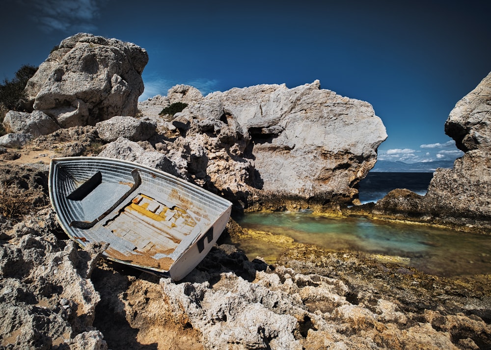 a boat sitting on top of a rocky beach