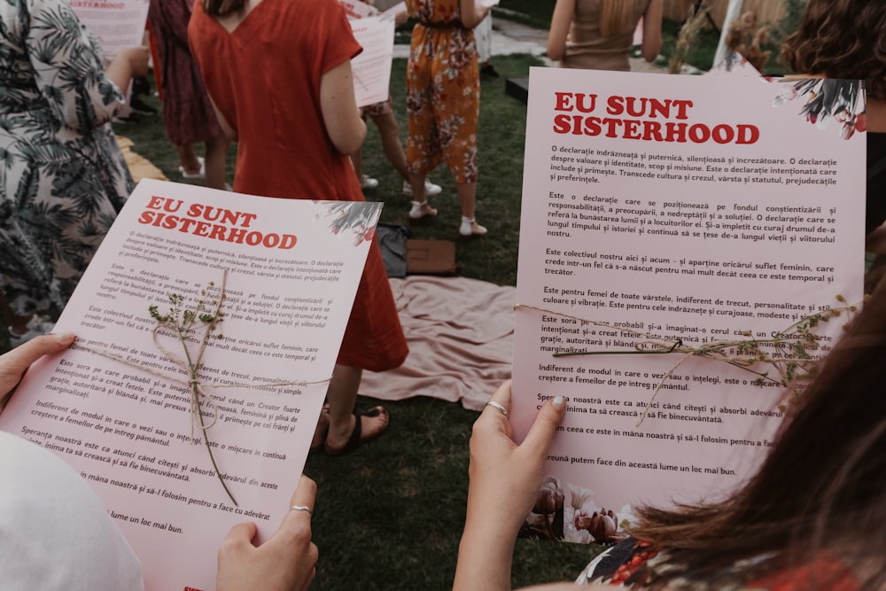 a group of people standing around each other holding papers