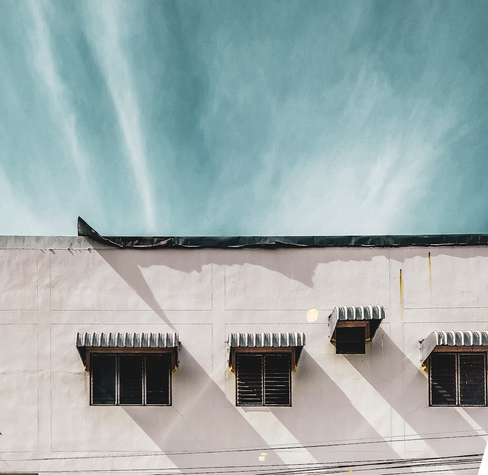 a white building with three windows and a sky background