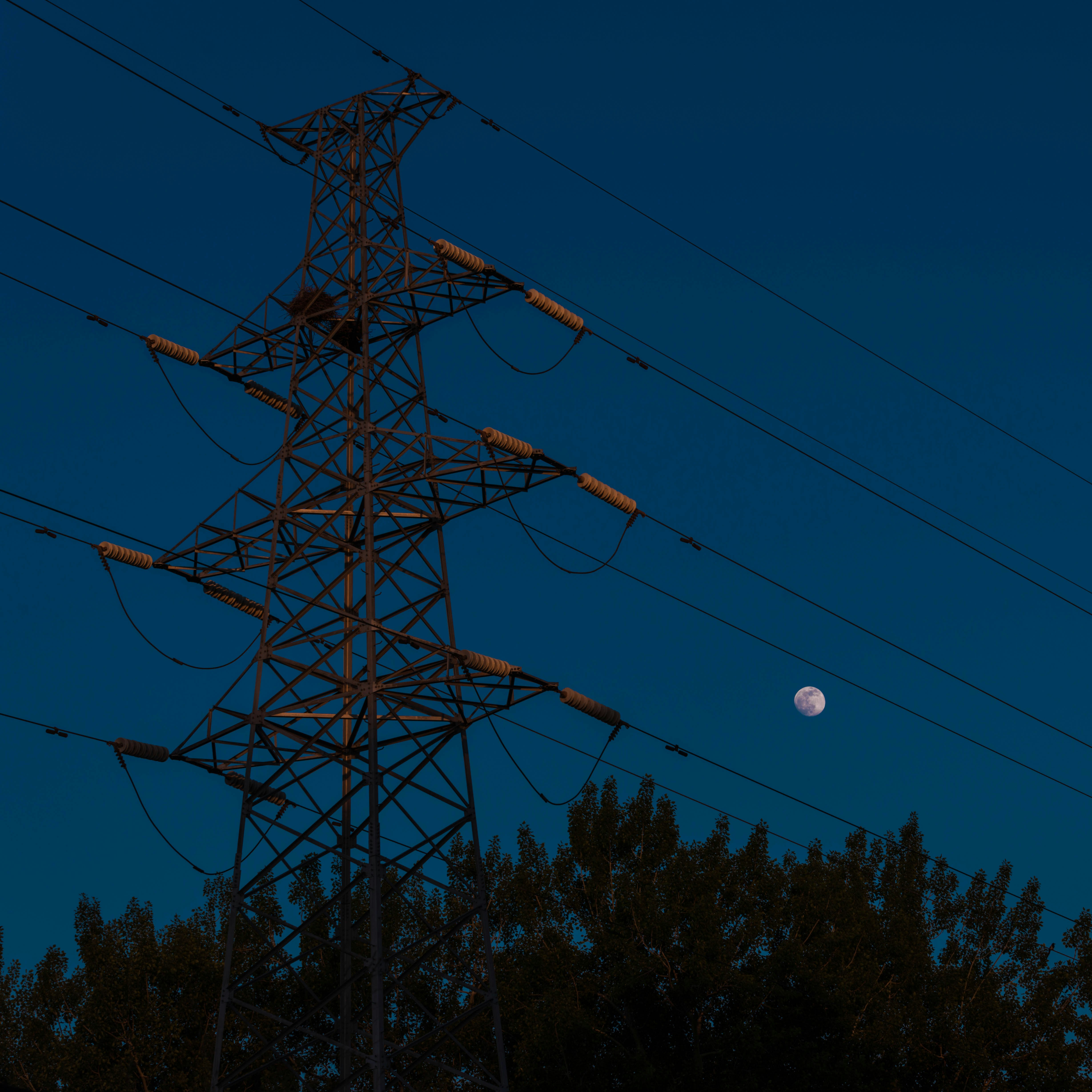 a full moon is seen behind power lines