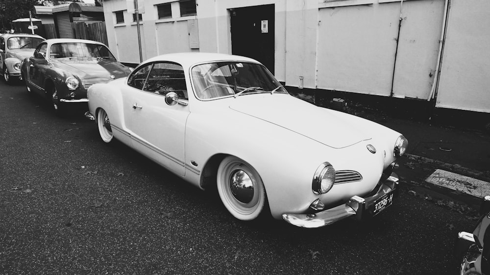 a black and white photo of a car parked in front of a building